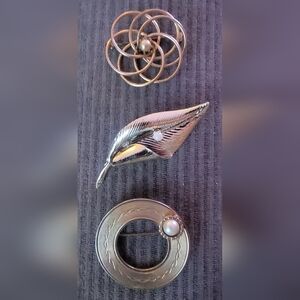 Lot includes three vintage brooches, with two being goldtone and one silvertone.